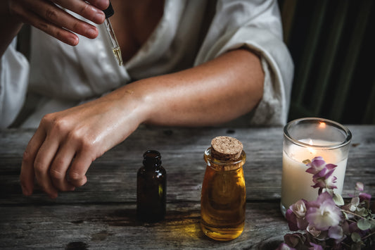 Create a cozy, artisanal workspace with scattered bottles of essential oils, a few spritz bottles filled with homemade room sprays, surrounded by lush green plants and dried herbs hanging in a sunlit,